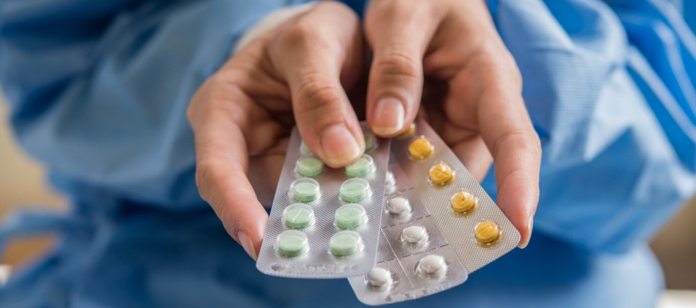 Mãos de uma mulher segurando cartelas de medicamentos