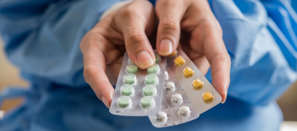 Mãos de uma mulher segurando cartelas de medicamentos