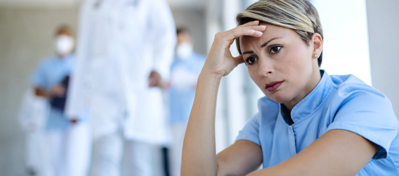 Enfermeira preocupada fazendo uma pausa e contemplando enquanto está sentada no saguão de uma clínica médica.