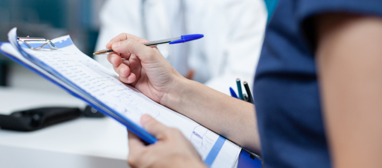 Close da mão paciente escrevendo informações médicas no documento