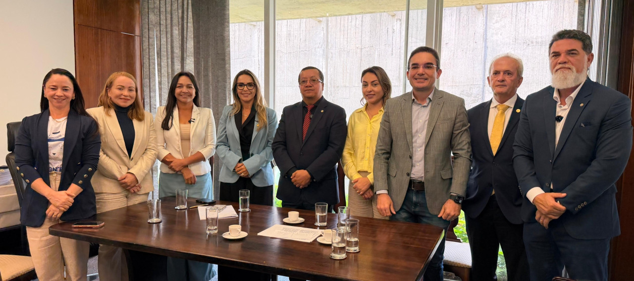 Um grupo de pessoas posando para foto atrás de uma mesa.