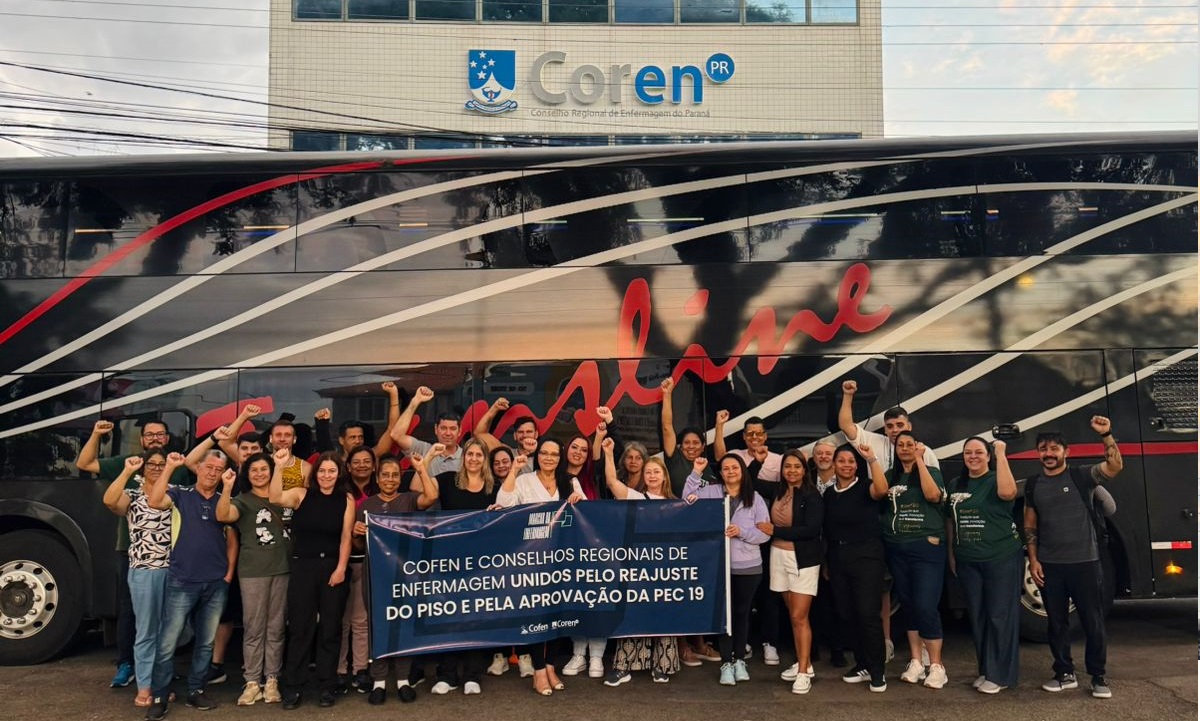 Profissionais em foto na frente do ônibus e da sede do Coren-PR