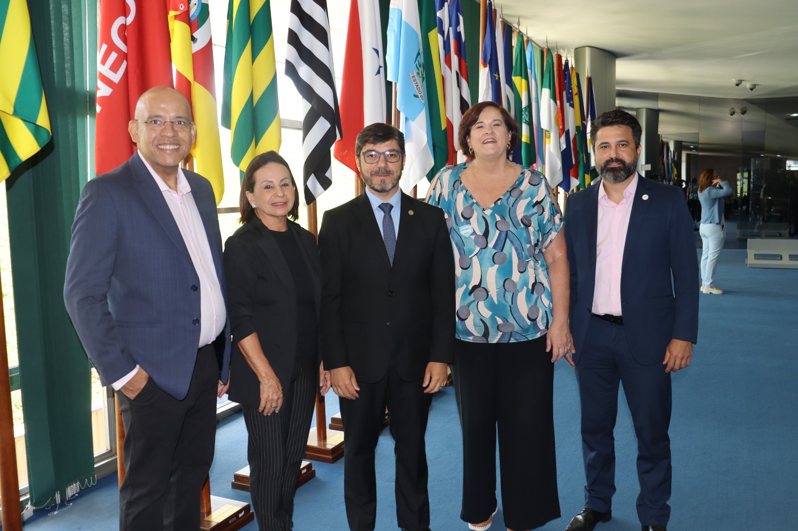 Pessoas pousando para foto e atrás bandeiras dos estados do Brasil