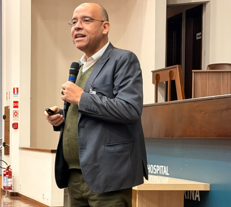 Pessoa em pé falando ao microfone para uma plateia