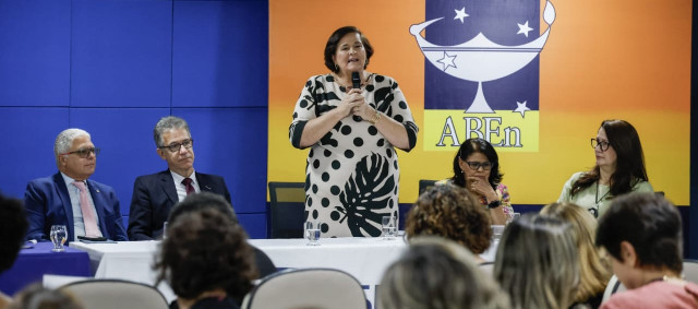 Pessoa em pé falando para pessoas sentadas em um auditório