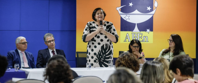 Pessoa em pé falando para pessoas sentadas em um auditório