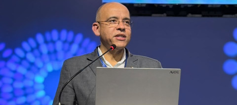 Pessoa em pé no púlpito falando para outras pessoas sentadas que estão participando de um evento