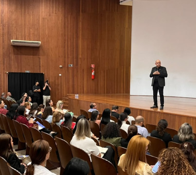 Uma pessoa em pé num auditório falando para as pessoas que estão sentadas